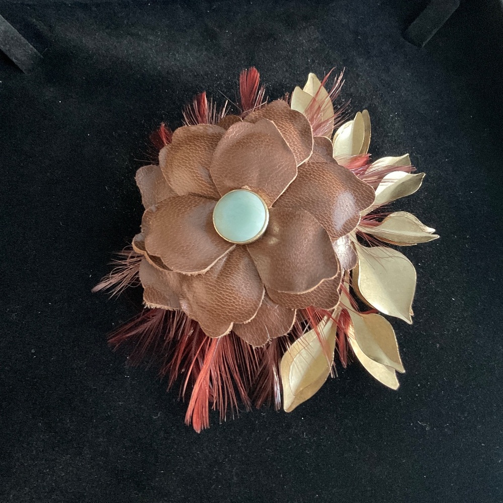 LEATHER, FEATHER & METAL BROOCH.  BLUE FACETED STONE IN CENTER OF FLOWER. SIGNED
